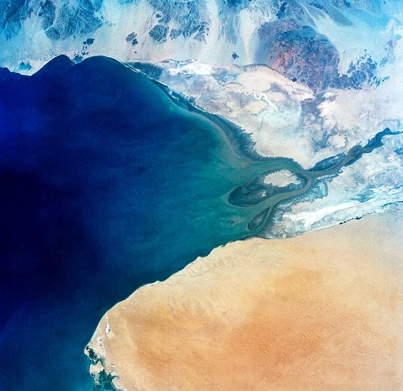A satellite image of Baja California, showing a mix of blue oceans and beige landmasses, bordered by a darker blue and orange/salmon-colored area.