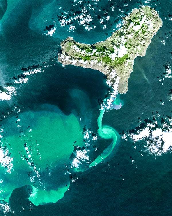 A satellite image of an underwater volcanic eruption, showing a vivid turquoise plume against darker water.
