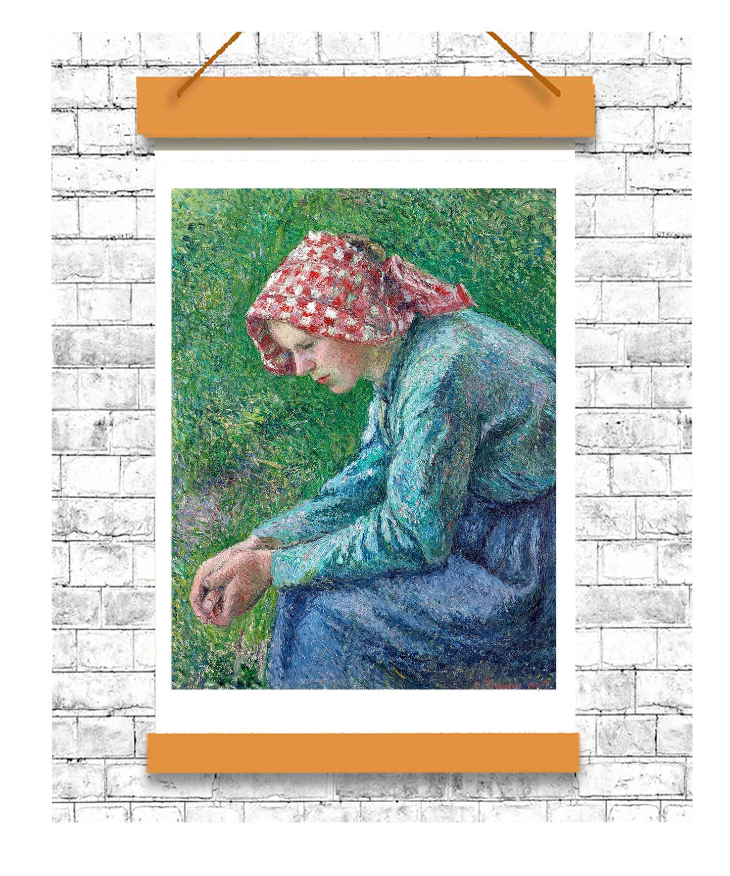 Painting of a woman in a floral headscarf sitting on grass, displayed on a white brick wall with an orange frame.