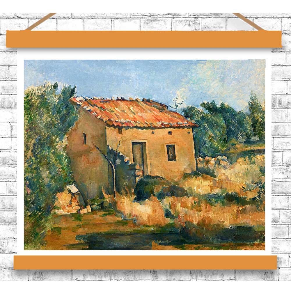 Painting of a rustic building with a person sitting on a rock, framed with an orange border on a white brick wall.