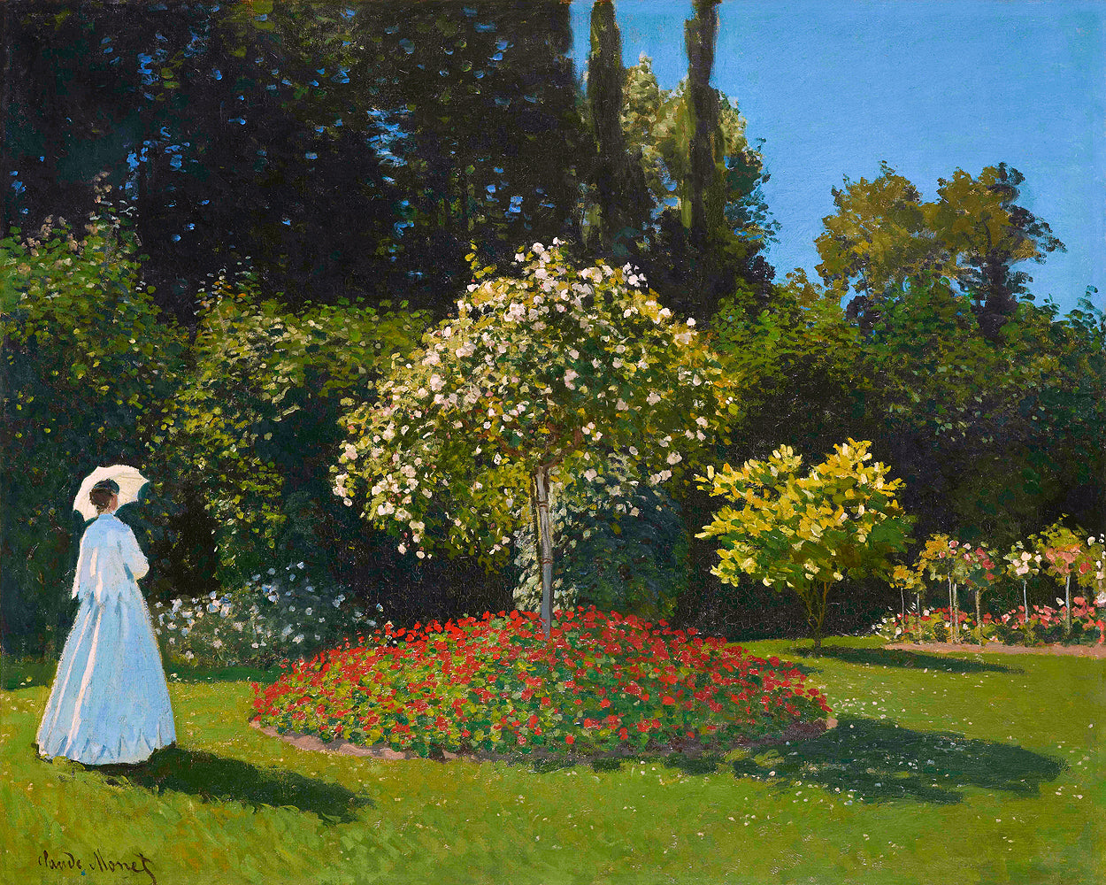A framed print of 'Lady in the garden' by Claude Monet, depicting a woman walking in a garden with a tree in bloom and colorful flowers.