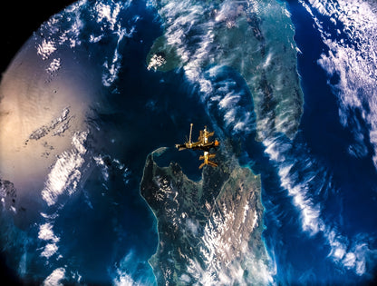 A landscape orientation photo of Earth from space with the space shuttle Atlantis visible over New Zealand.