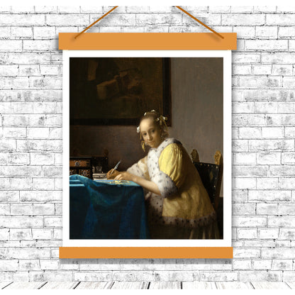 A printed art piece depicting a woman in historical clothing writing a letter, framed in a black frame.