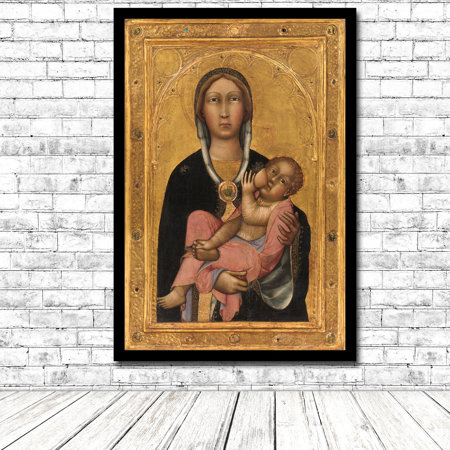 A printed artwork depicting the Madonna and Child, with the child resting in his mother's lap, set against a golden background, framed in a simple black frame.