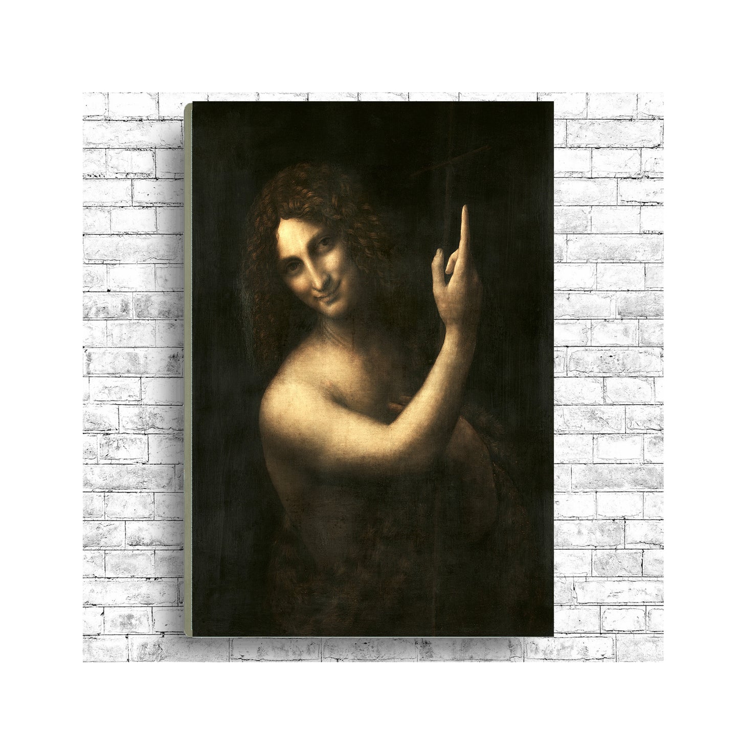 A framed print of 'Saint John the Baptist' by Leonardo Di Vinci, showing the subject with a finger pointing upwards, in a dark and moody portrait style.