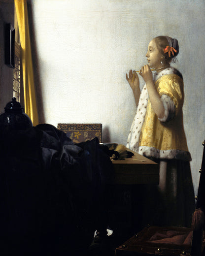 A printed reproduction of Johannes Vermeer's painting 'Young Woman with a Pearl Necklace', featuring a young woman in a baroque style dress, standing beside a window.