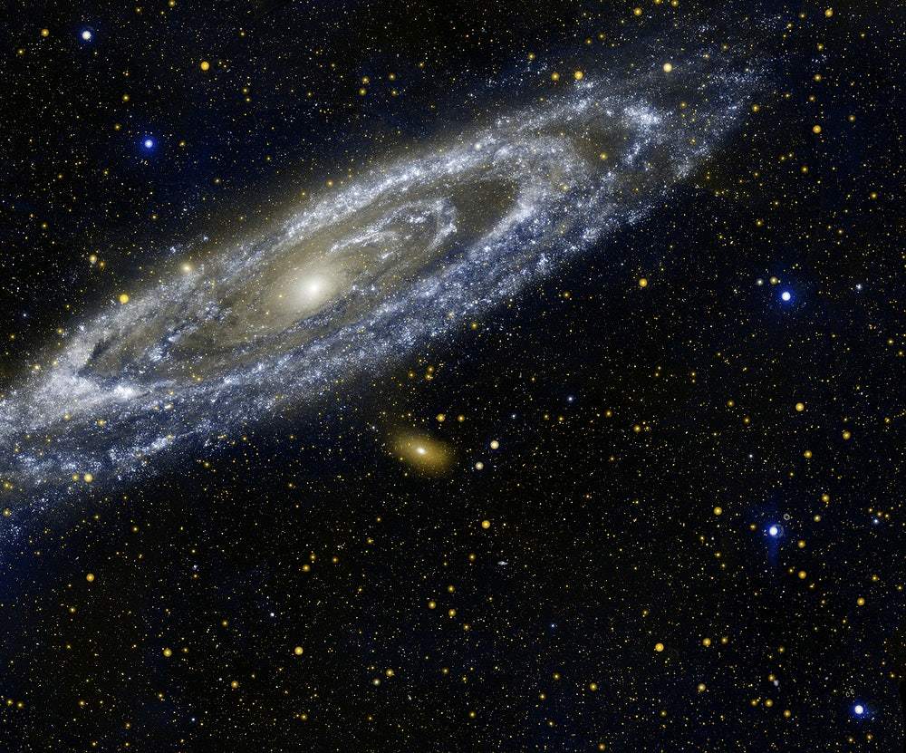 A printed image of the Andromeda galaxy, showcasing a spiral galaxy with a bright core and surrounded by a dark expanse of space sprinkled with stars.