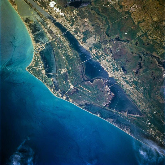 A color satellite image of a coastal area with urban and green spaces visible.