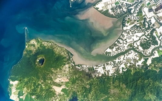 A panoramic photo of a volcanic landscape on Earth, likely the Cosiguina Volcano, viewed from a high altitude or space with surrounding greenery and bodies of water.