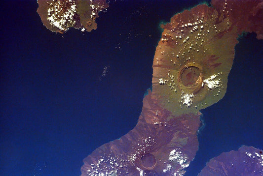 A NASA photograph featuring the Galapagos Islands viewed from space, with a blend of blue and purple hues representing different terrains.