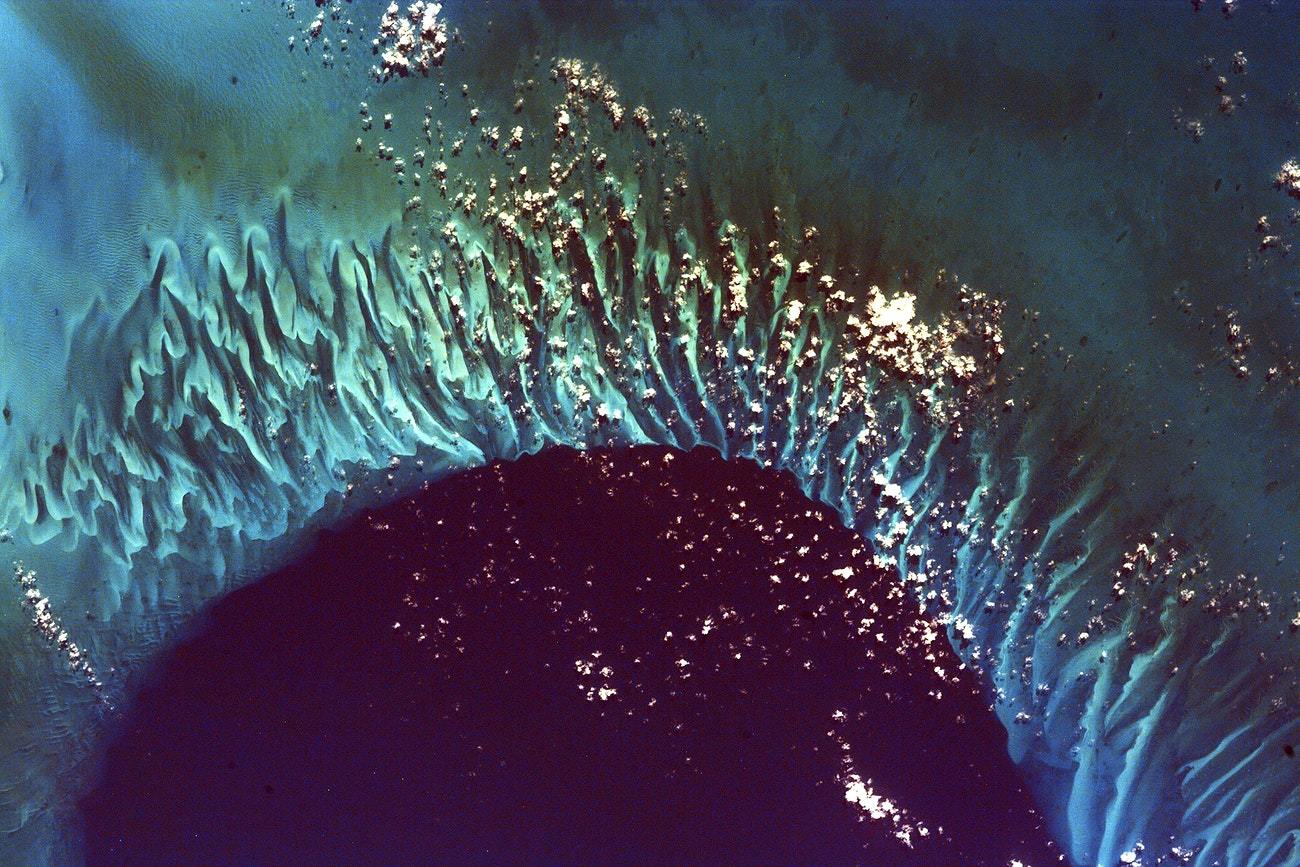 A satellite image of a body of water, presumably an ocean, with varying shades of blue and turquoise, processed in a way that resembles artistic brush strokes.